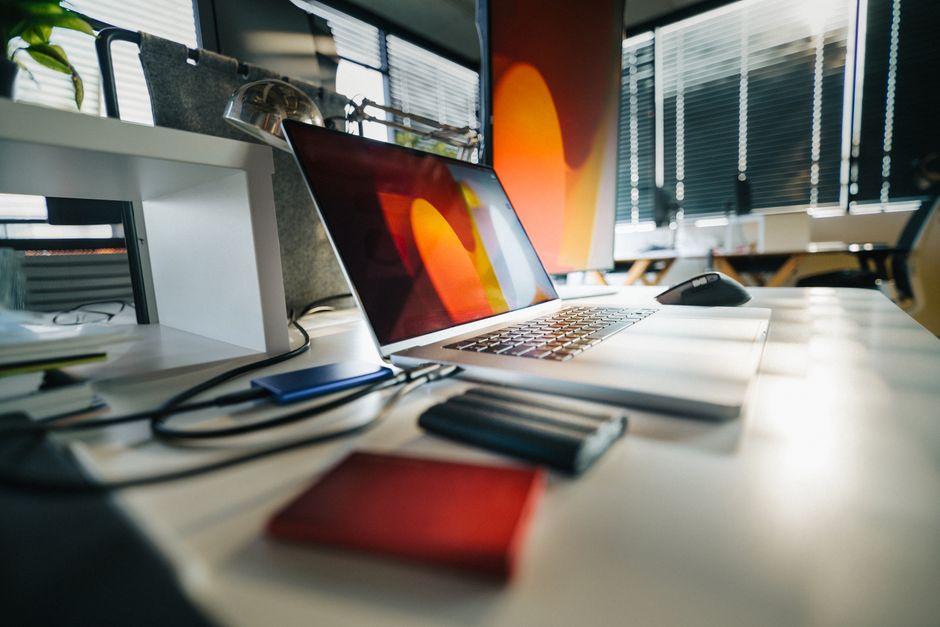 A tidy desk with a laptop and external drives